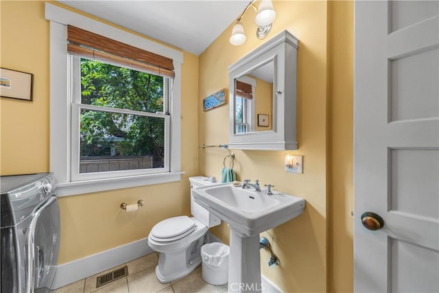 bathroom featuring toilet, independent washer and dryer, visible vents, tile patterned flooring, and baseboards