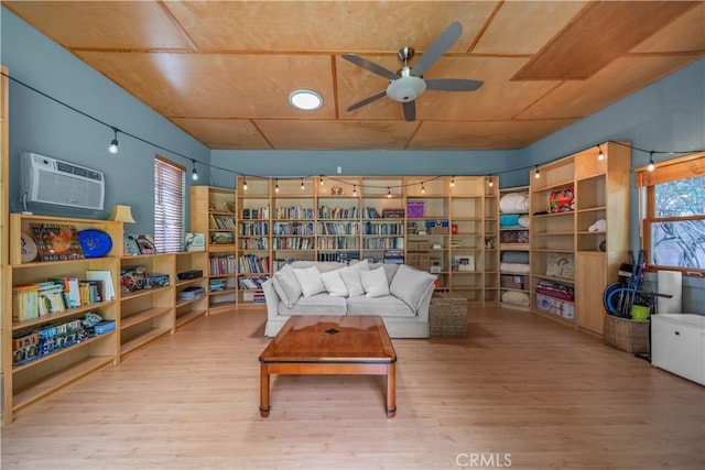 living room featuring a ceiling fan, a wall mounted air conditioner, and wood finished floors