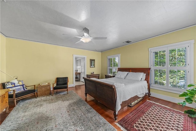 bedroom with a ceiling fan, baseboards, visible vents, and wood finished floors