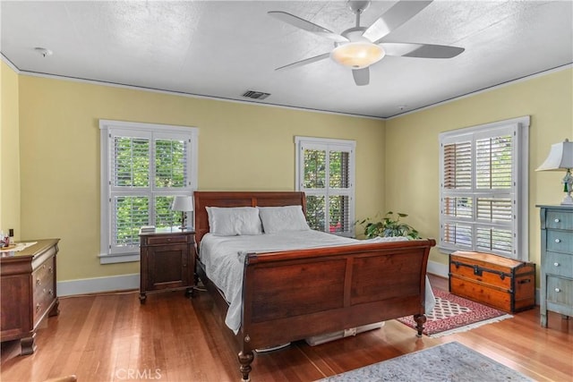 bedroom with baseboards, visible vents, a ceiling fan, and wood finished floors