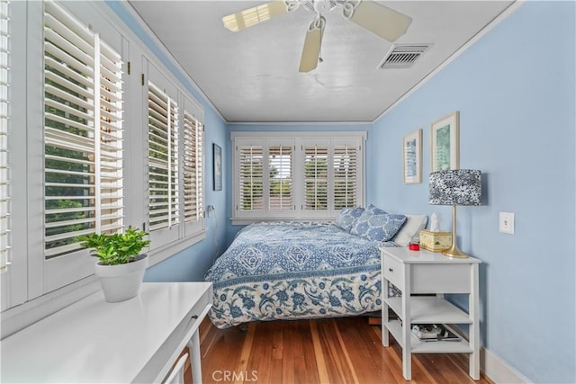 bedroom featuring crown molding, a ceiling fan, visible vents, and wood finished floors