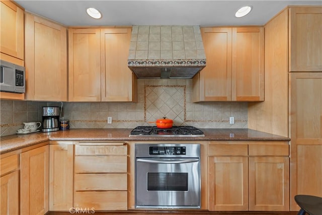 kitchen featuring light brown cabinets, recessed lighting, wall chimney range hood, stainless steel appliances, and tasteful backsplash