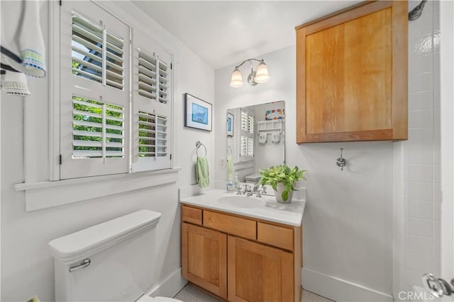 bathroom with vanity, toilet, baseboards, and a healthy amount of sunlight