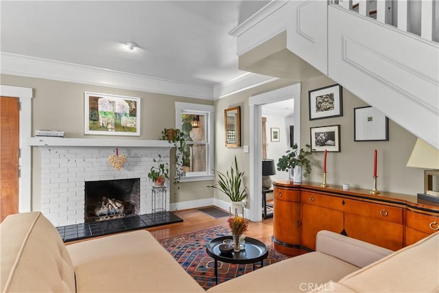 living area featuring crown molding, baseboards, wood finished floors, and a fireplace
