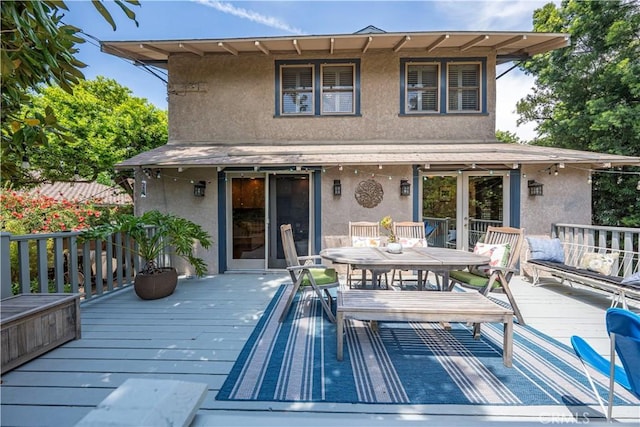 back of property featuring stucco siding, a deck, and outdoor dining space