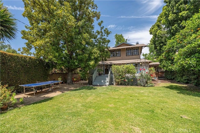 rear view of property with a fenced backyard, a yard, and stairway