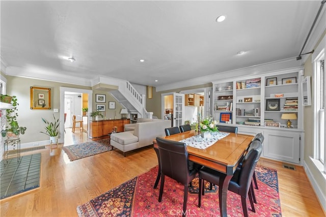 dining room featuring stairway, crown molding, light wood-style flooring, and visible vents