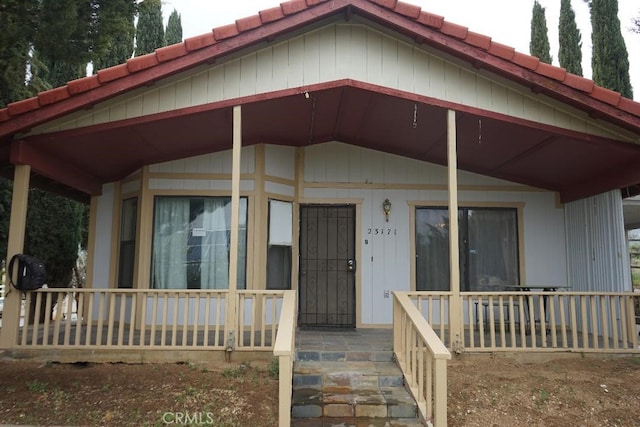 farmhouse featuring covered porch and a tile roof