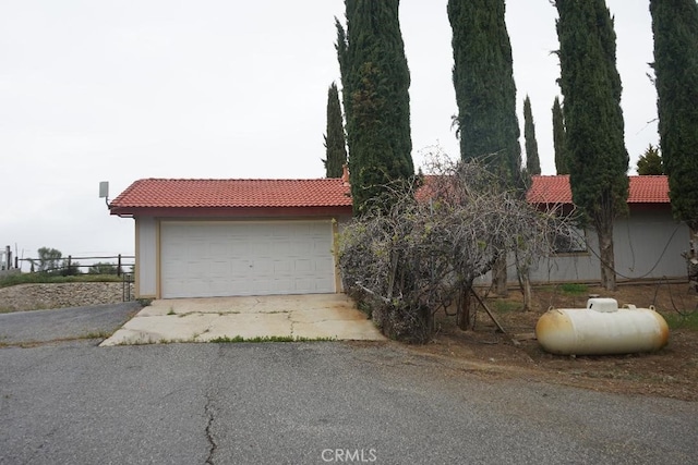 view of property exterior featuring a tiled roof, fence, and a garage