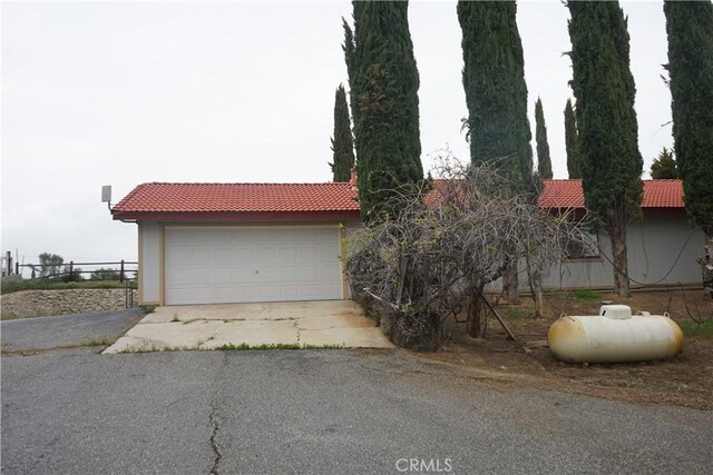 exterior space with a tiled roof, fence, and a detached garage