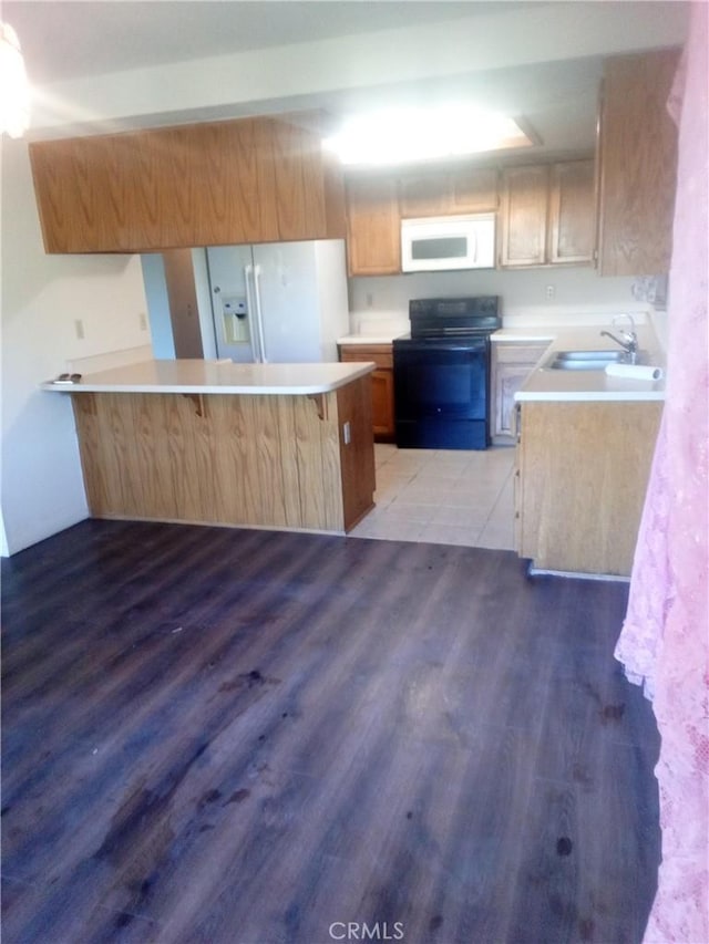 23171 Woodford Tehachapi Rd, Tehachapi, CA 93561 - kitchen with white appliances, light countertops, a sink, wood finished floors, and a peninsula