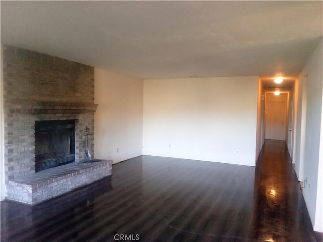 23171 Woodford Tehachapi Rd, Tehachapi, CA 93561 - unfurnished living room featuring dark wood finished floors and a brick fireplace