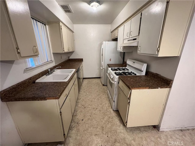 kitchen with under cabinet range hood, white appliances, visible vents, a sink, and dark countertops