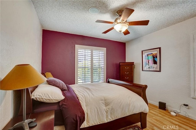 bedroom with a textured ceiling, a textured wall, and wood finished floors