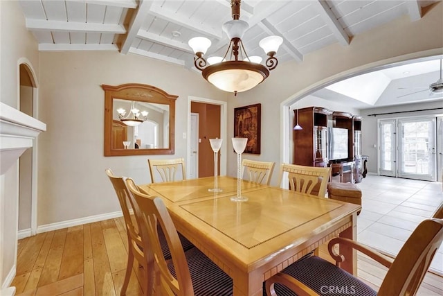 dining area featuring lofted ceiling with beams, light wood finished floors, an inviting chandelier, arched walkways, and baseboards