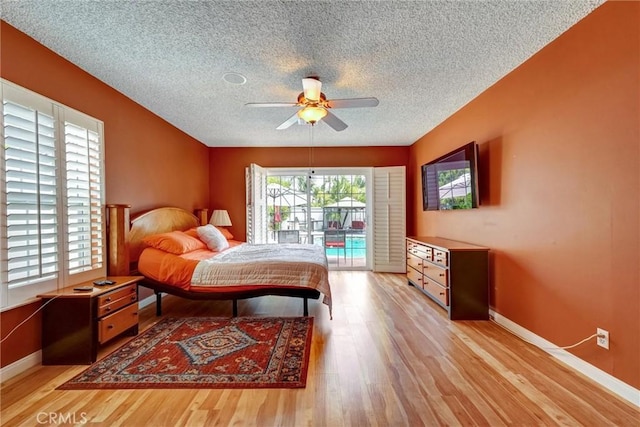 bedroom with light wood finished floors, a textured ceiling, baseboards, and access to exterior