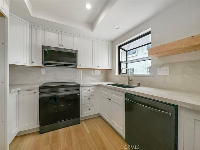 kitchen with light countertops, white cabinetry, stainless steel appliances, and a sink