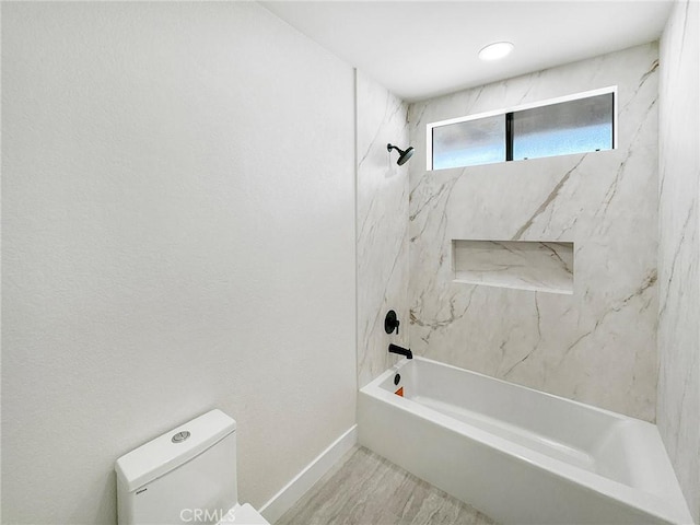 bathroom with toilet, baseboards, and shower / bathtub combination