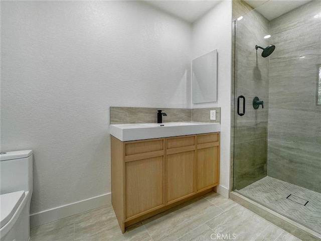 bathroom featuring a shower stall, baseboards, vanity, and toilet
