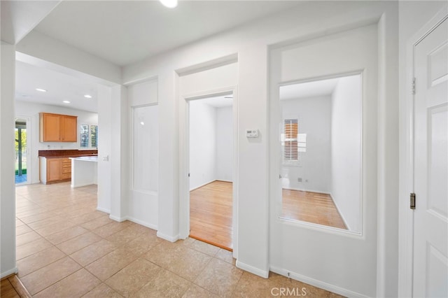 hall with baseboards, recessed lighting, and light tile patterned flooring