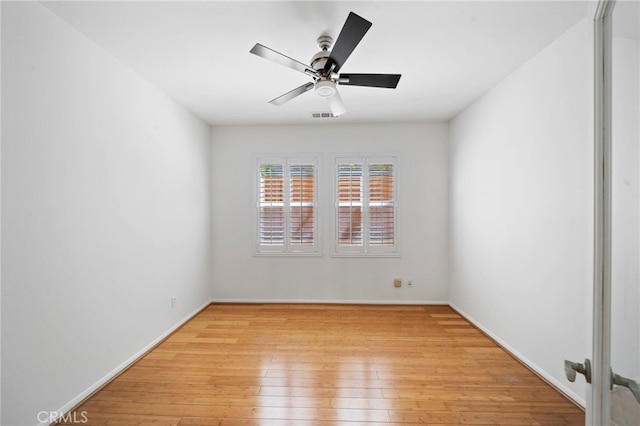 spare room featuring light wood-type flooring, visible vents, baseboards, and ceiling fan
