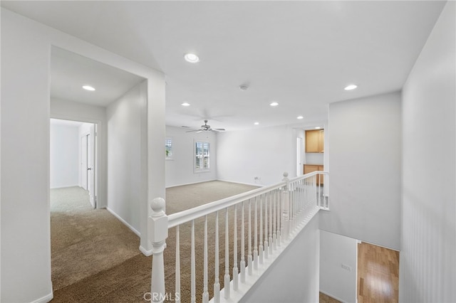 hallway with baseboards, an upstairs landing, recessed lighting, and carpet