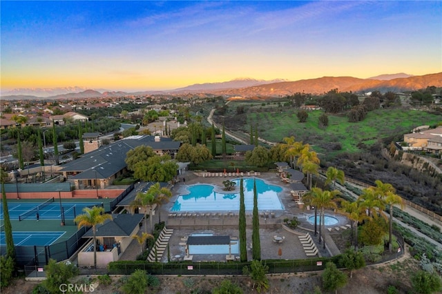 aerial view at dusk of a mountain view and view of pool