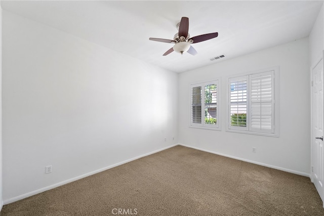 empty room with carpet, visible vents, and baseboards