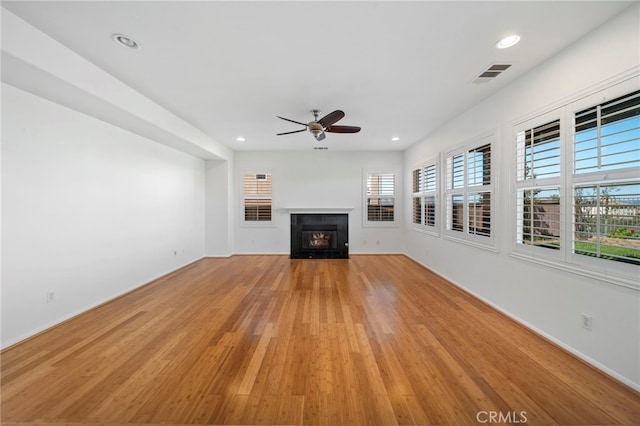 unfurnished living room with visible vents, light wood finished floors, a ceiling fan, baseboards, and a fireplace with flush hearth