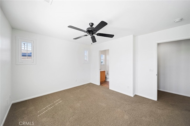 unfurnished bedroom featuring ensuite bathroom, carpet floors, baseboards, and multiple windows