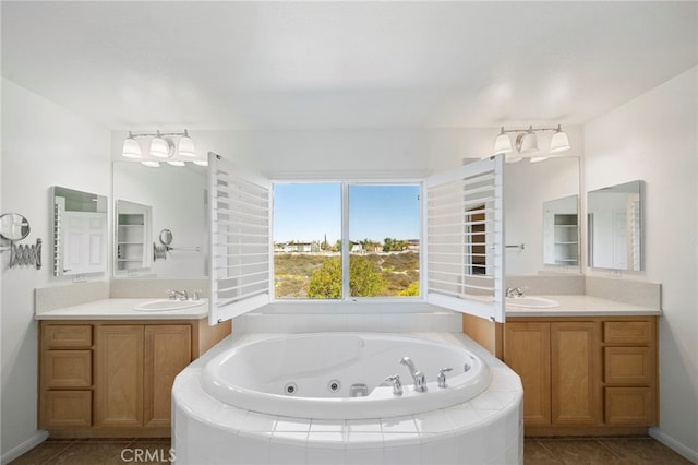 full bath featuring two vanities, a jetted tub, and tile patterned flooring