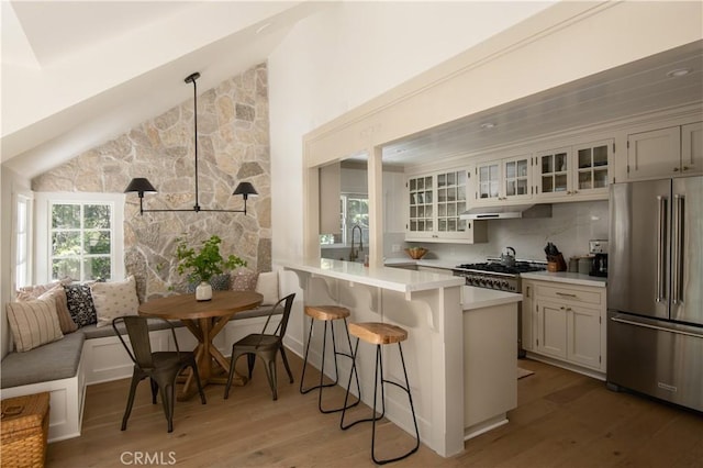 920 Oak Rd, Lake Arrowhead, CA 92385 - kitchen with high end fridge, light wood-style flooring, glass insert cabinets, a kitchen breakfast bar, and light countertops