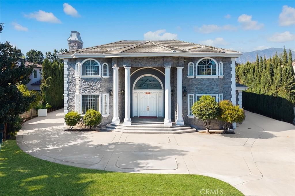 greek revival inspired property featuring stone siding and a chimney