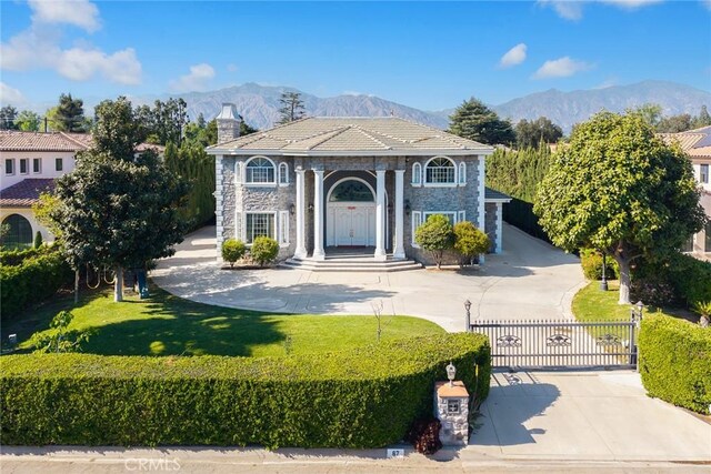 67 W Wistaria Ave, Arcadia, CA 91007 - view of front of home with stone siding, curved driveway, a gate, and a mountain view