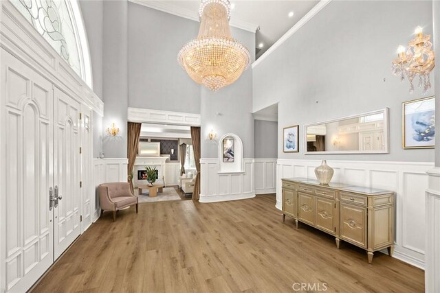 67 W Wistaria Ave, Arcadia, CA 91007 - sitting room with a chandelier, ornamental molding, a decorative wall, a towering ceiling, and light wood-type flooring