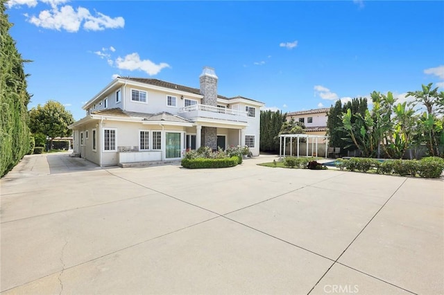 67 W Wistaria Ave, Arcadia, CA 91007 - back of property featuring a chimney, stucco siding, a balcony, concrete driveway, and french doors