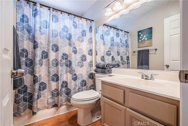 bathroom with toilet, a shower with curtain, vanity, and wood finished floors