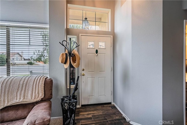 entryway with dark wood finished floors, baseboards, and a textured wall