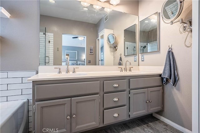 ensuite bathroom with a sink, double vanity, visible vents, and wood finished floors