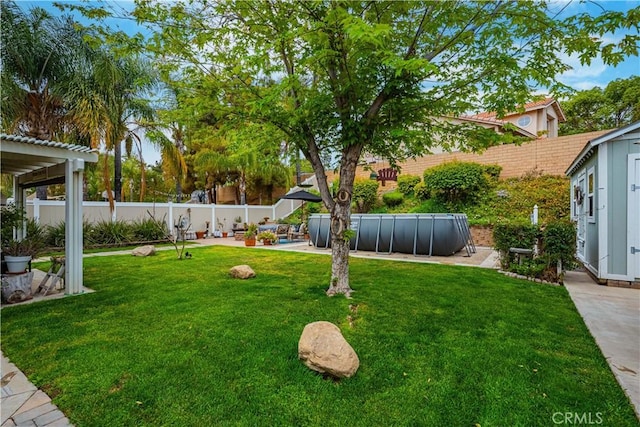 view of yard with a patio, a storage unit, an outdoor structure, a fenced backyard, and a fenced in pool