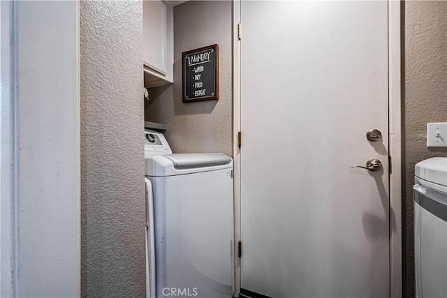laundry area with washer / dryer, cabinet space, and a textured wall