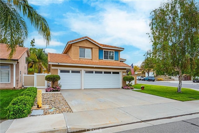 traditional home with fence, driveway, a tile roof, a garage, and stucco siding