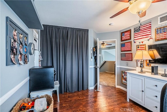 interior space featuring dark wood-style flooring, baseboards, a ceiling fan, and visible vents