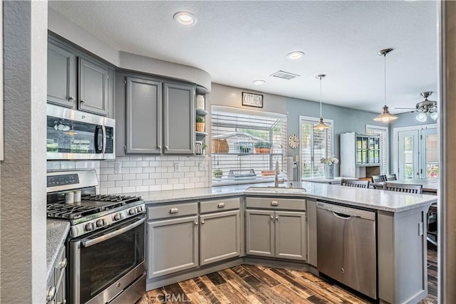 kitchen featuring visible vents, gray cabinets, a peninsula, stainless steel appliances, and dark wood-style floors