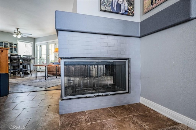 room details with ceiling fan, a brick fireplace, baseboards, and a textured wall
