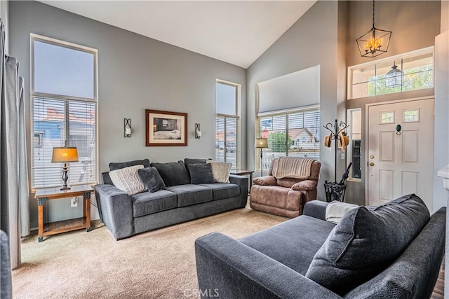 living area with a notable chandelier, high vaulted ceiling, and carpet floors
