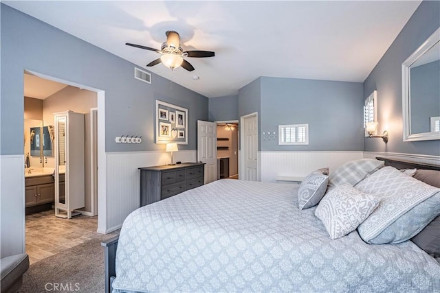 carpeted bedroom featuring ceiling fan, visible vents, and a wainscoted wall