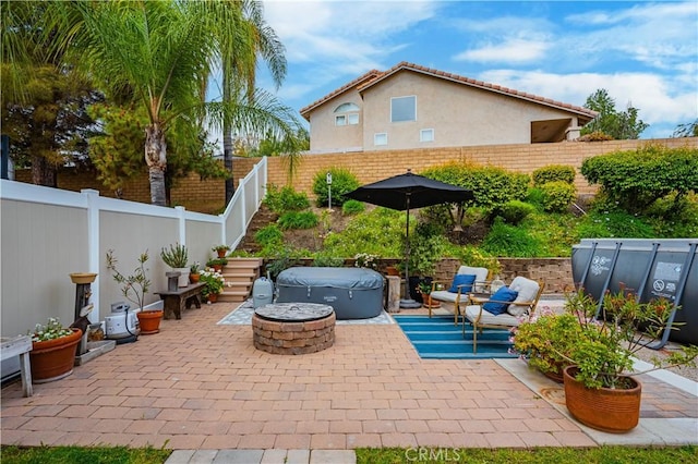 view of patio / terrace featuring a fenced backyard, a fire pit, and a hot tub