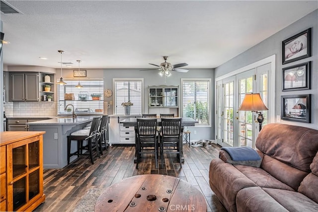 living area featuring ceiling fan, visible vents, and dark wood-type flooring