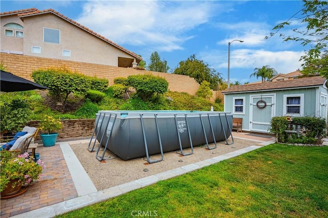 view of pool featuring a yard, fence, a fenced in pool, and an outbuilding
